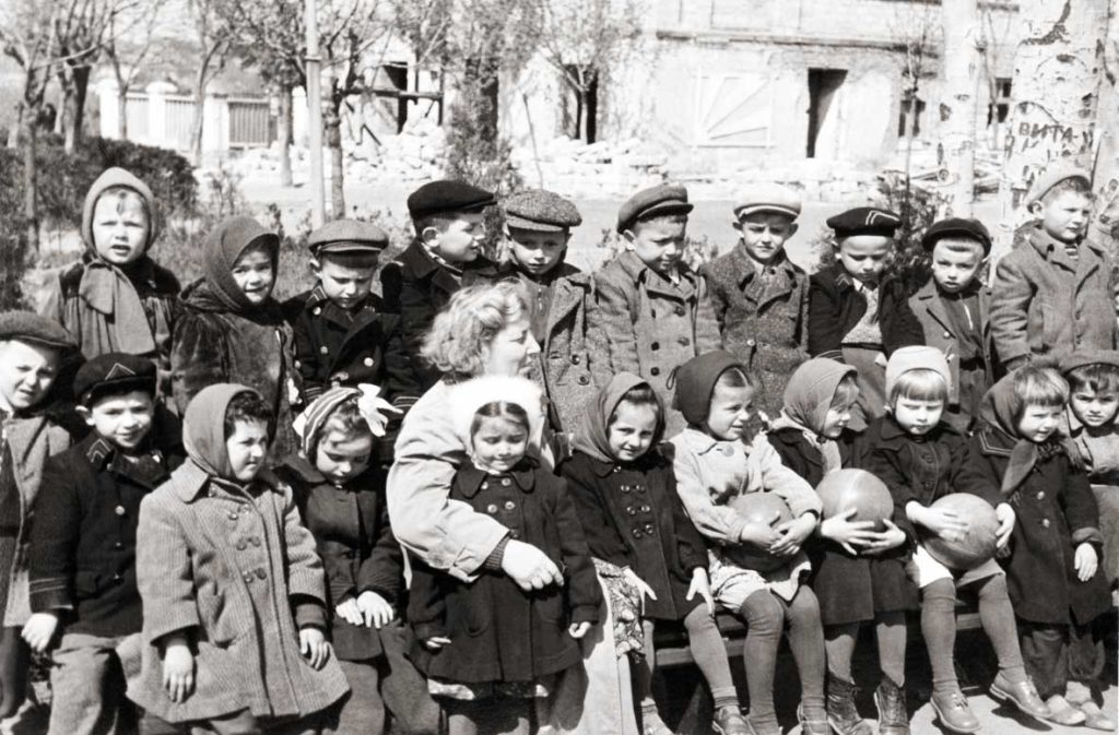 Каршенбойл Ц.С. с воспитанниками на фоне разрушенного детского сада №2